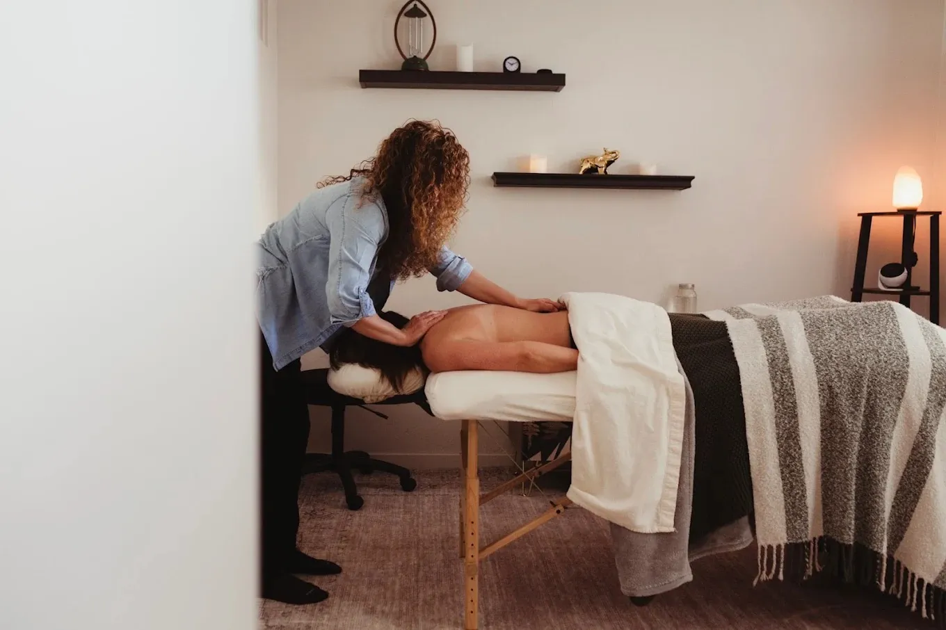 A massage therapist working on a client in a warmly lit treatment room at Live Well Durango.