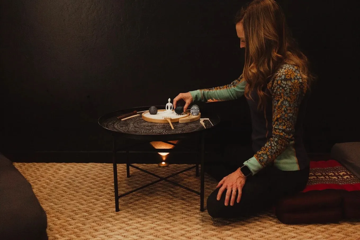 A practitioner arranging a meditation tray by candlelight in a quiet room at Live Well Durango.